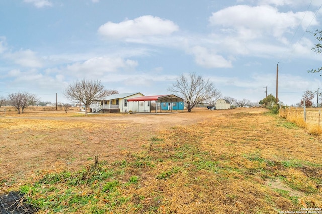 view of yard featuring a carport, a rural view, and a storage shed