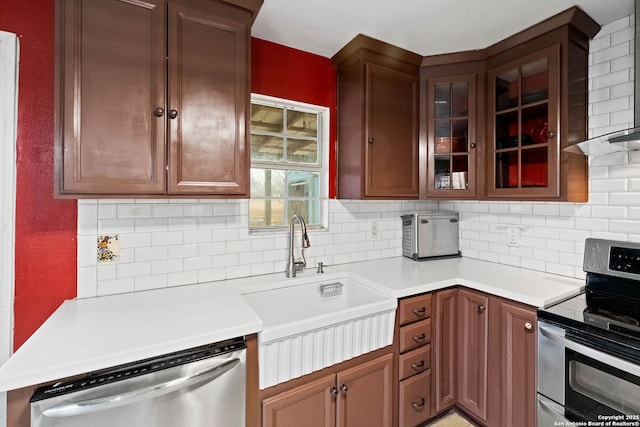 kitchen with tasteful backsplash, appliances with stainless steel finishes, sink, and wall chimney range hood