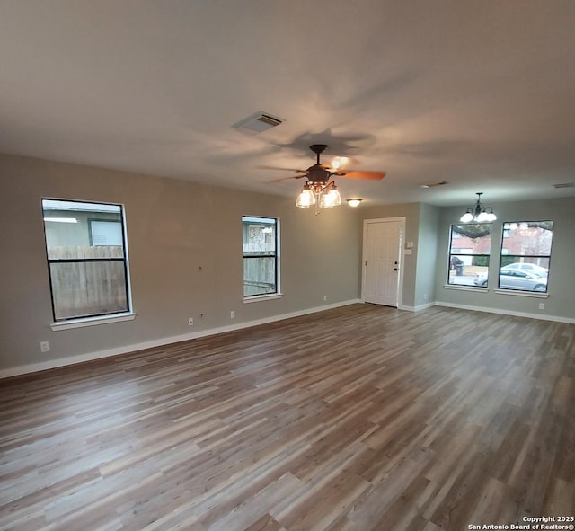 unfurnished living room with wood-type flooring and ceiling fan with notable chandelier