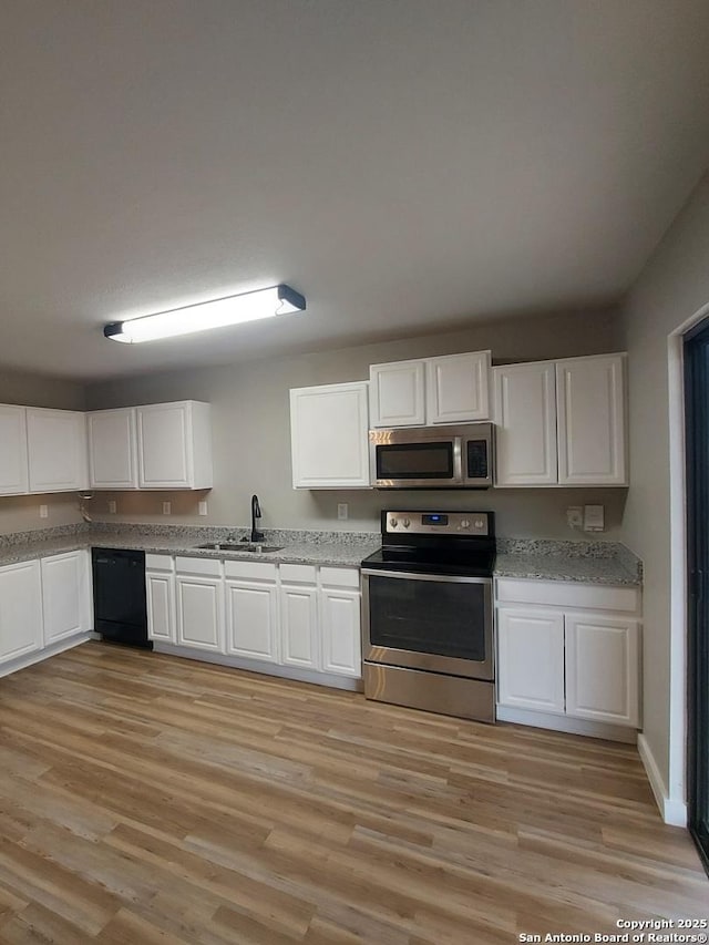 kitchen featuring appliances with stainless steel finishes, sink, white cabinets, and light hardwood / wood-style floors