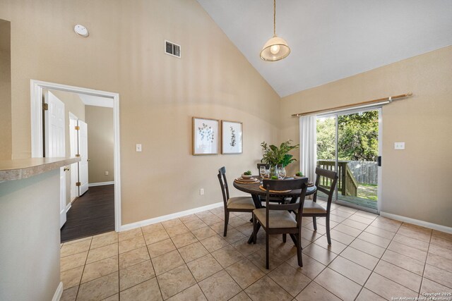 tiled dining space featuring high vaulted ceiling