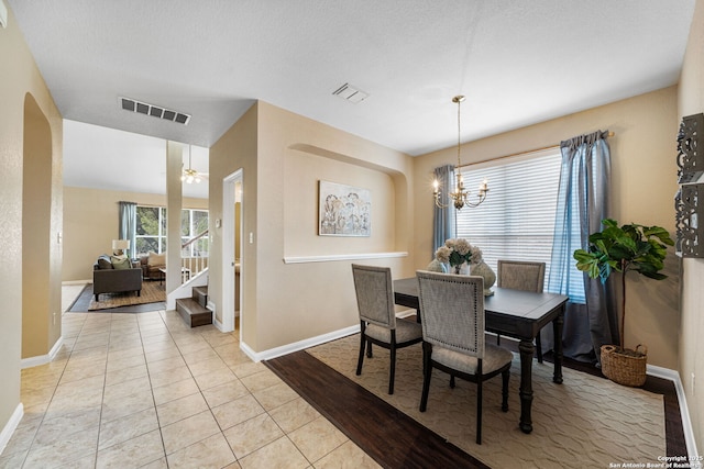 tiled dining area with a textured ceiling and ceiling fan with notable chandelier