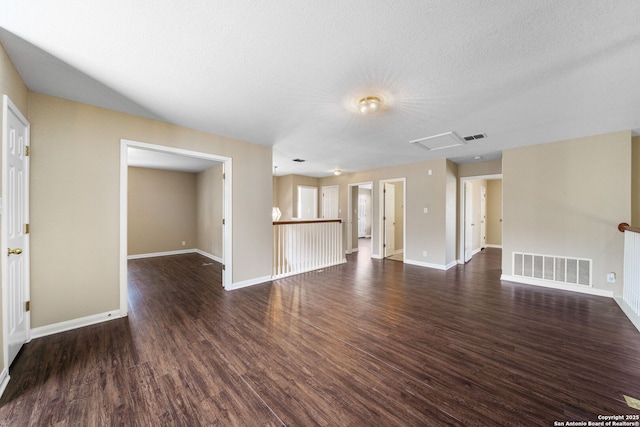 unfurnished living room featuring dark wood-type flooring and a textured ceiling