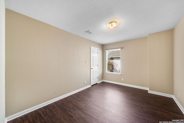 spare room featuring a textured ceiling and dark hardwood / wood-style floors