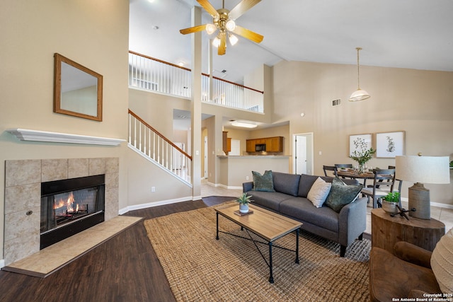 living room with ceiling fan, vaulted ceiling, wood-type flooring, and a fireplace