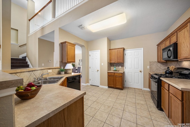 kitchen featuring light tile patterned floors, sink, backsplash, black appliances, and kitchen peninsula