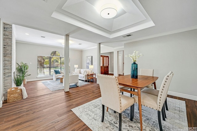 dining space featuring crown molding, a tray ceiling, and hardwood / wood-style flooring