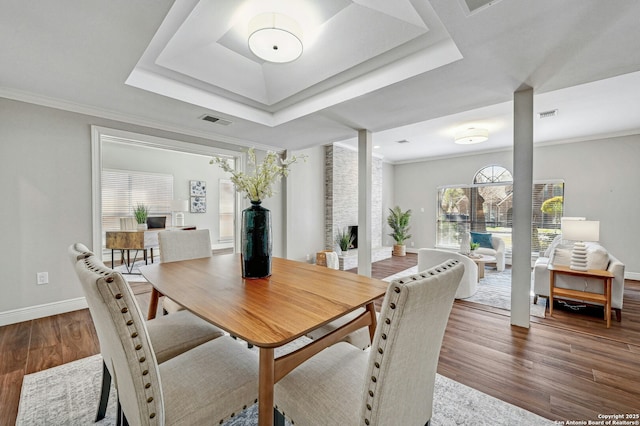 dining room featuring dark wood-type flooring, ornamental molding, and a raised ceiling