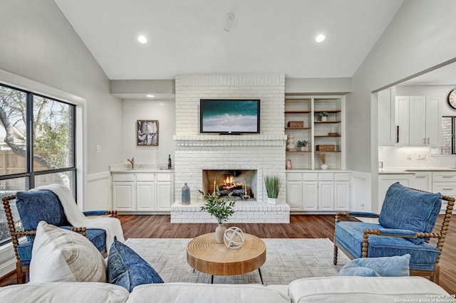 living room featuring hardwood / wood-style flooring, a fireplace, and vaulted ceiling