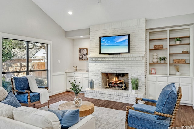 living room featuring lofted ceiling, a brick fireplace, and wood-type flooring