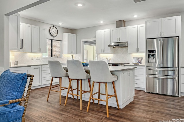 kitchen featuring a breakfast bar, white cabinets, a center island, stainless steel refrigerator with ice dispenser, and dark wood-type flooring