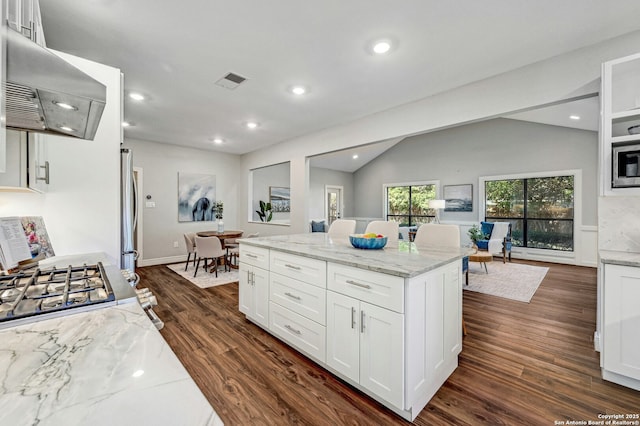 kitchen with lofted ceiling, dark hardwood / wood-style flooring, light stone countertops, range hood, and white cabinets