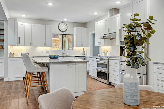 kitchen with light hardwood / wood-style flooring, stainless steel appliances, a center island, and white cabinets