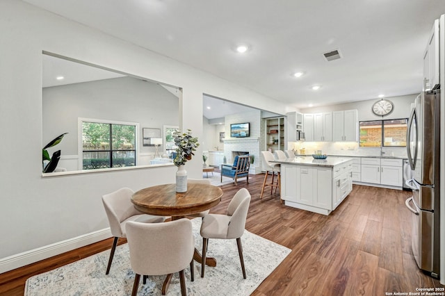 dining area featuring hardwood / wood-style flooring, lofted ceiling, sink, and a brick fireplace