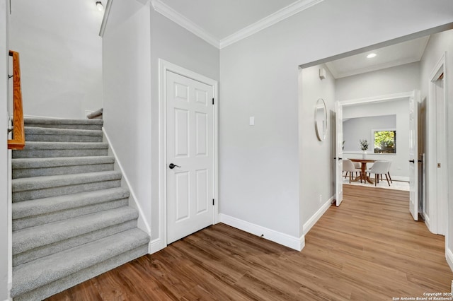 stairway with wood-type flooring and crown molding