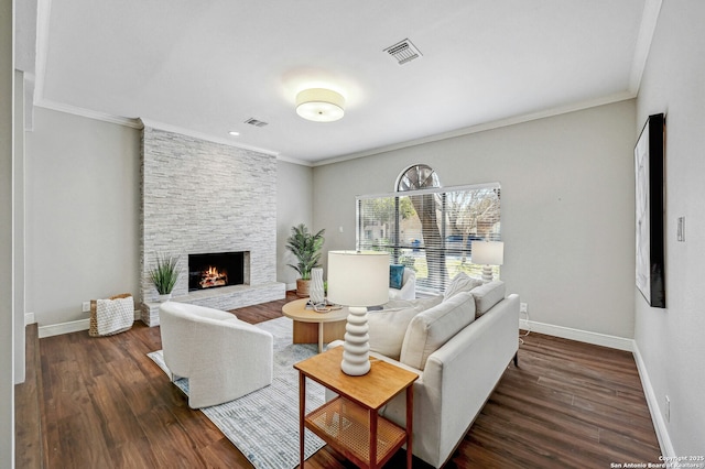 living room with ornamental molding, a stone fireplace, and dark hardwood / wood-style floors