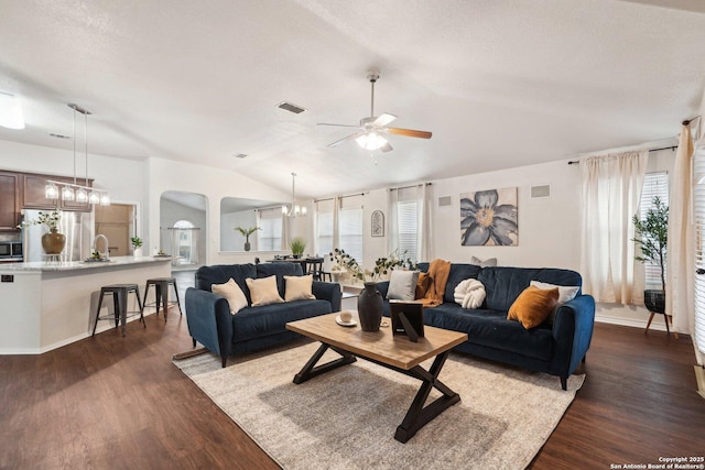 living room featuring lofted ceiling, ceiling fan with notable chandelier, dark hardwood / wood-style floors, and a textured ceiling