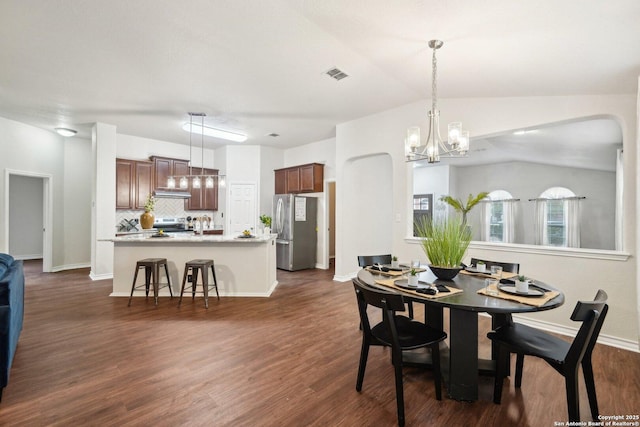 dining room featuring dark wood-type flooring, an inviting chandelier, and vaulted ceiling