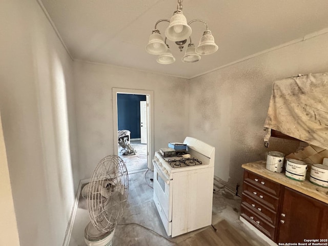 kitchen with crown molding, decorative light fixtures, white gas stove, and a notable chandelier