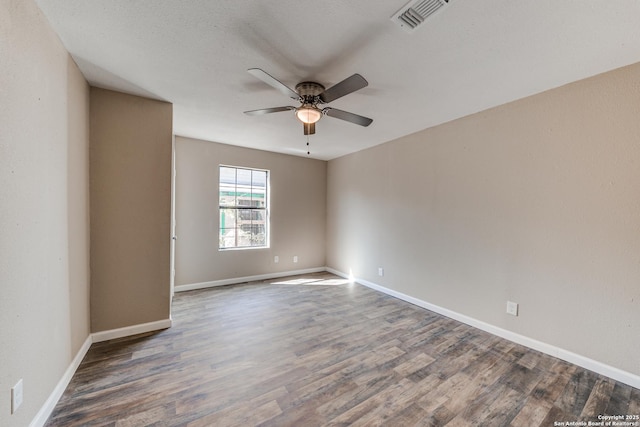 unfurnished room featuring dark wood-style flooring, visible vents, ceiling fan, and baseboards