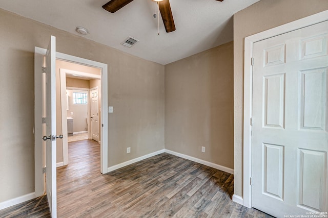 empty room with visible vents, ceiling fan, baseboards, and wood finished floors