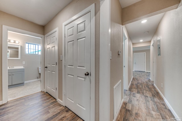 corridor featuring recessed lighting, visible vents, baseboards, and wood finished floors