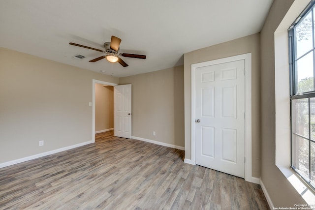 unfurnished bedroom with a ceiling fan, light wood-type flooring, visible vents, and baseboards