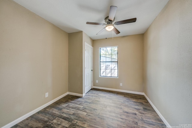 spare room with a ceiling fan, dark wood-style flooring, and baseboards