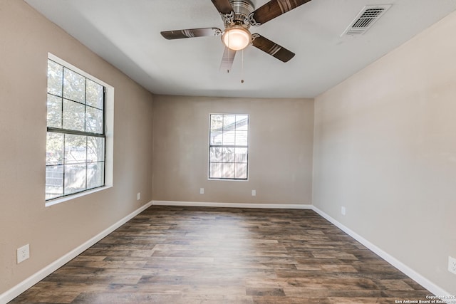 unfurnished room featuring dark wood-style floors, baseboards, visible vents, and ceiling fan