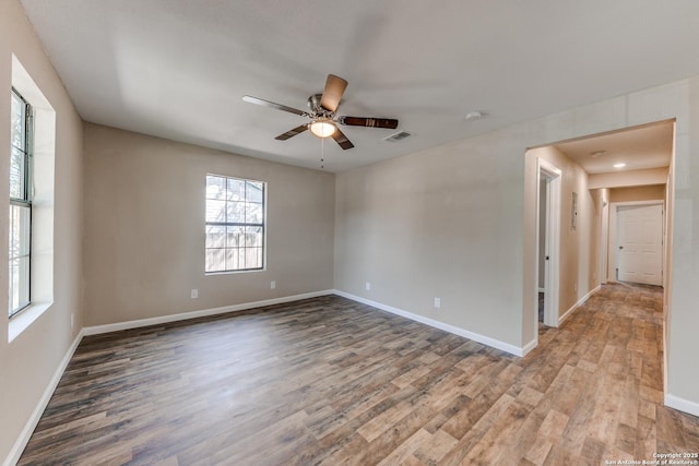 unfurnished room with baseboards, visible vents, and wood finished floors