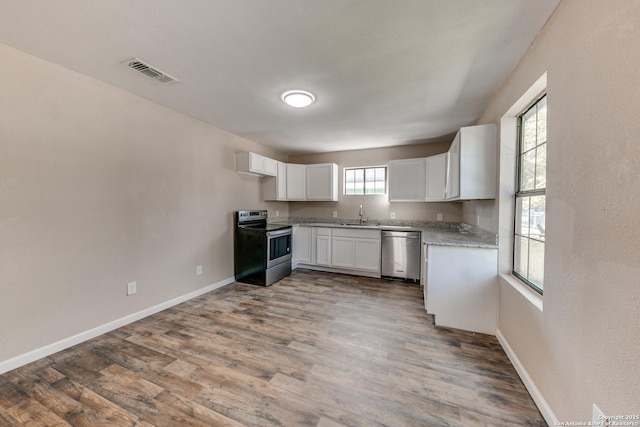 kitchen featuring visible vents, dark wood-type flooring, stainless steel appliances, white cabinetry, and a sink