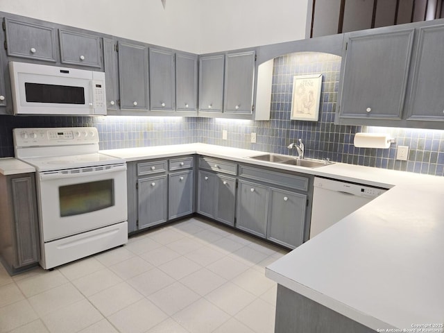 kitchen featuring gray cabinets, sink, backsplash, and white appliances