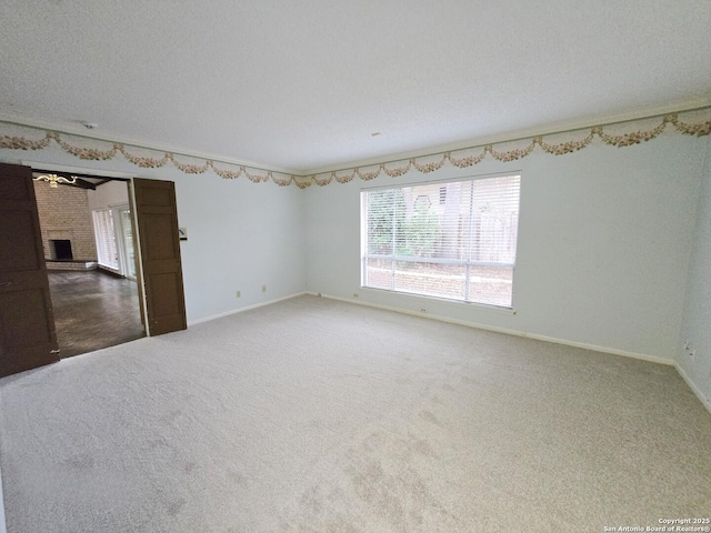 empty room with ornamental molding, carpet, a textured ceiling, and a fireplace