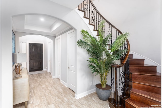 foyer entrance with a tray ceiling and ornamental molding