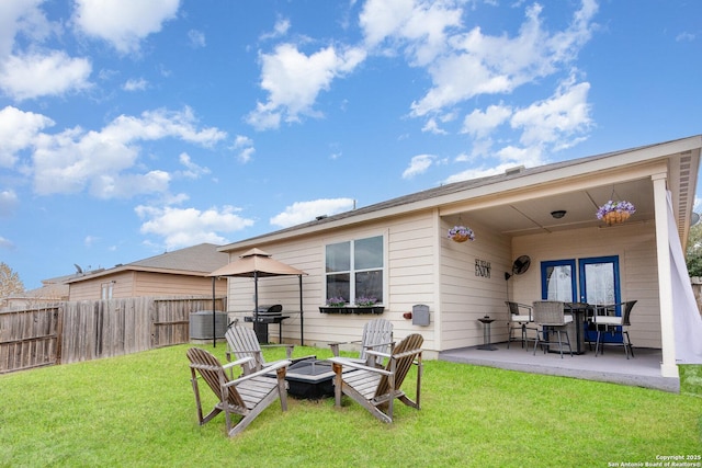 back of house featuring a lawn, a patio area, and a fire pit