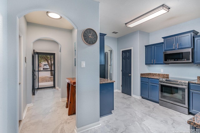 kitchen featuring stainless steel appliances, dark stone counters, and blue cabinetry