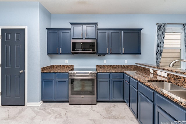 kitchen featuring blue cabinetry, appliances with stainless steel finishes, sink, and dark stone counters