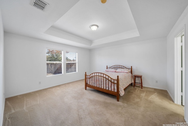 bedroom with light carpet and a tray ceiling