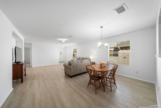 dining area with light hardwood / wood-style flooring and a chandelier