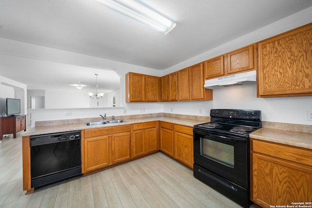 kitchen with sink, light wood-type flooring, kitchen peninsula, pendant lighting, and black appliances