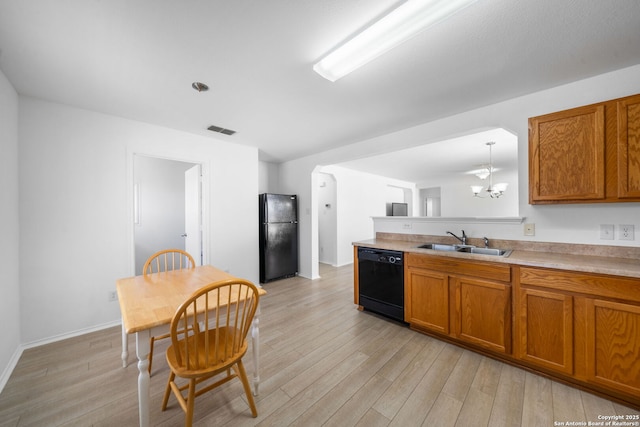 kitchen with pendant lighting, sink, light wood-type flooring, black appliances, and an inviting chandelier