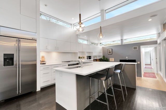 kitchen with white cabinetry, stainless steel built in fridge, dark wood-type flooring, and decorative light fixtures