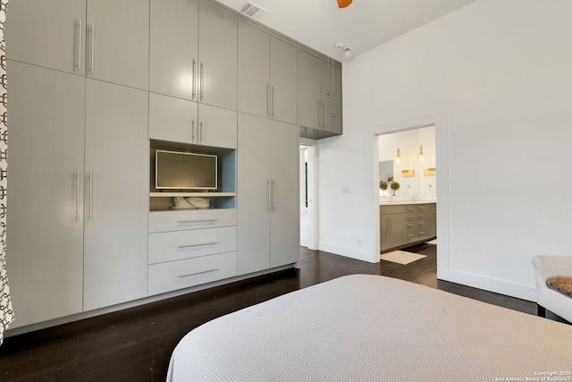 bedroom featuring ensuite bathroom, dark hardwood / wood-style flooring, and a high ceiling