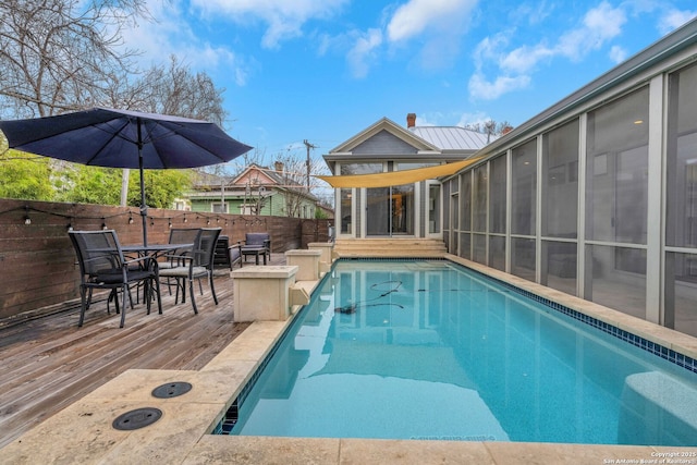 view of swimming pool with a wooden deck and a sunroom