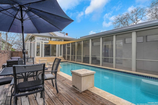 view of pool with a sunroom and a deck