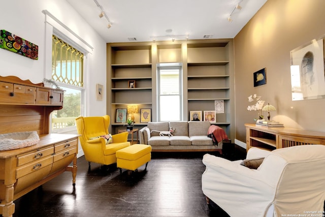 living room with built in shelves, dark hardwood / wood-style flooring, and rail lighting