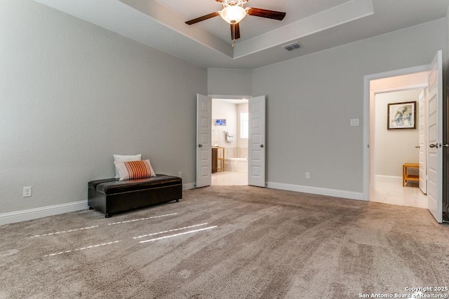 unfurnished bedroom featuring light carpet, a raised ceiling, and ensuite bathroom