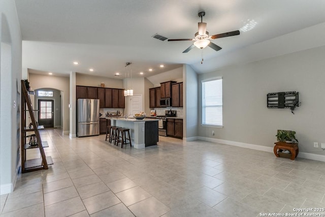 kitchen with pendant lighting, a breakfast bar area, ceiling fan, appliances with stainless steel finishes, and a center island