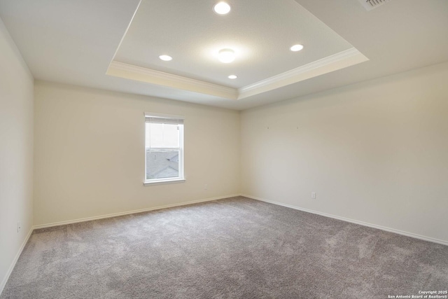 carpeted spare room with a tray ceiling and ornamental molding