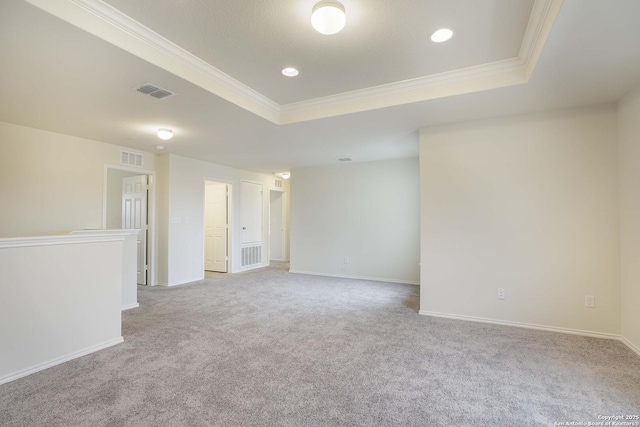 carpeted spare room with crown molding and a raised ceiling